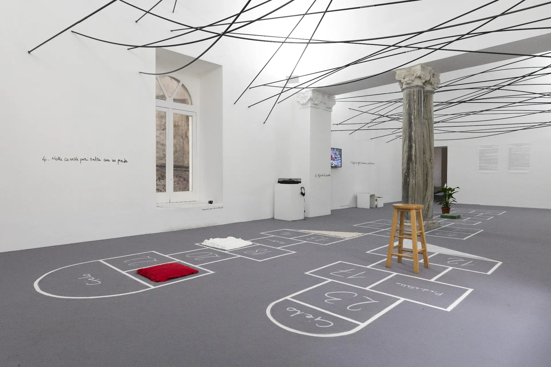Il gioco della campana — installation view with red cushion, stool and hopscotch grids