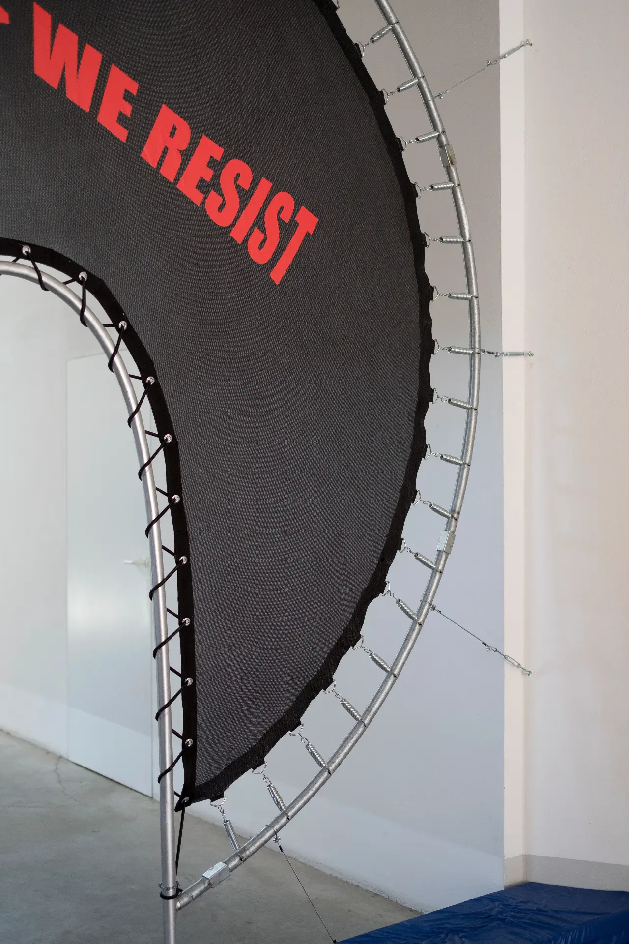 Radical Power — detail of the tensioned trampoline surface with the slogan “In <power> we resist”